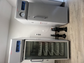 Calibrated and qualified 2–8°C refrigerator and −30°C freezer with continuous temperature monitoring via Wi-Fi data logger and remote alarm notifications, supported by an emergency generator and UPS providing up to 30 minutes of backup power.